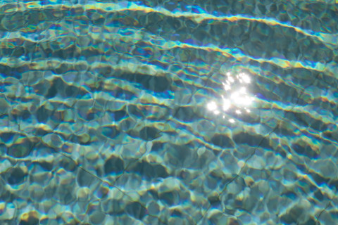 Crystal clear saltwater pool with sun reflections